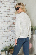 Back view of a woman in a light-colored stylish vacation top for women paired with jeans and sunglasses
