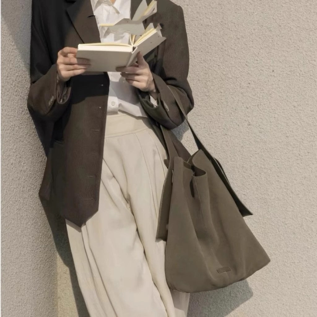 Stylish woman holding a book with a suede large capacity shoulder bag in a modern outfit