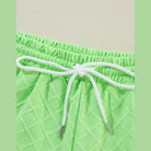 Close-up of green summer casual drawstring shorts outfit with textured fabric and white drawstring