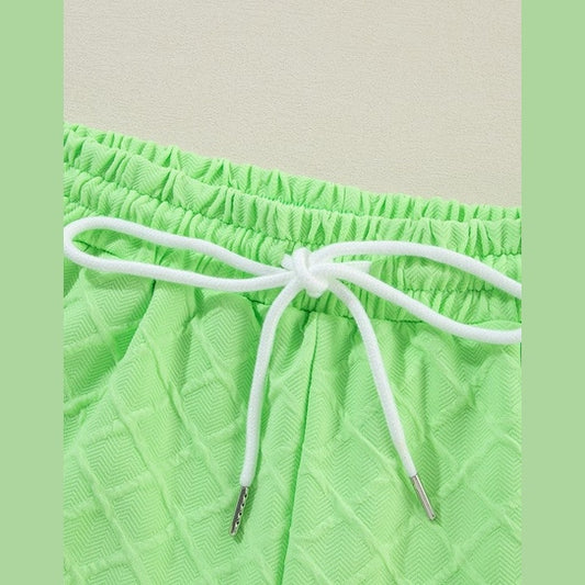 Close-up of green summer casual drawstring shorts outfit with textured fabric and white drawstring