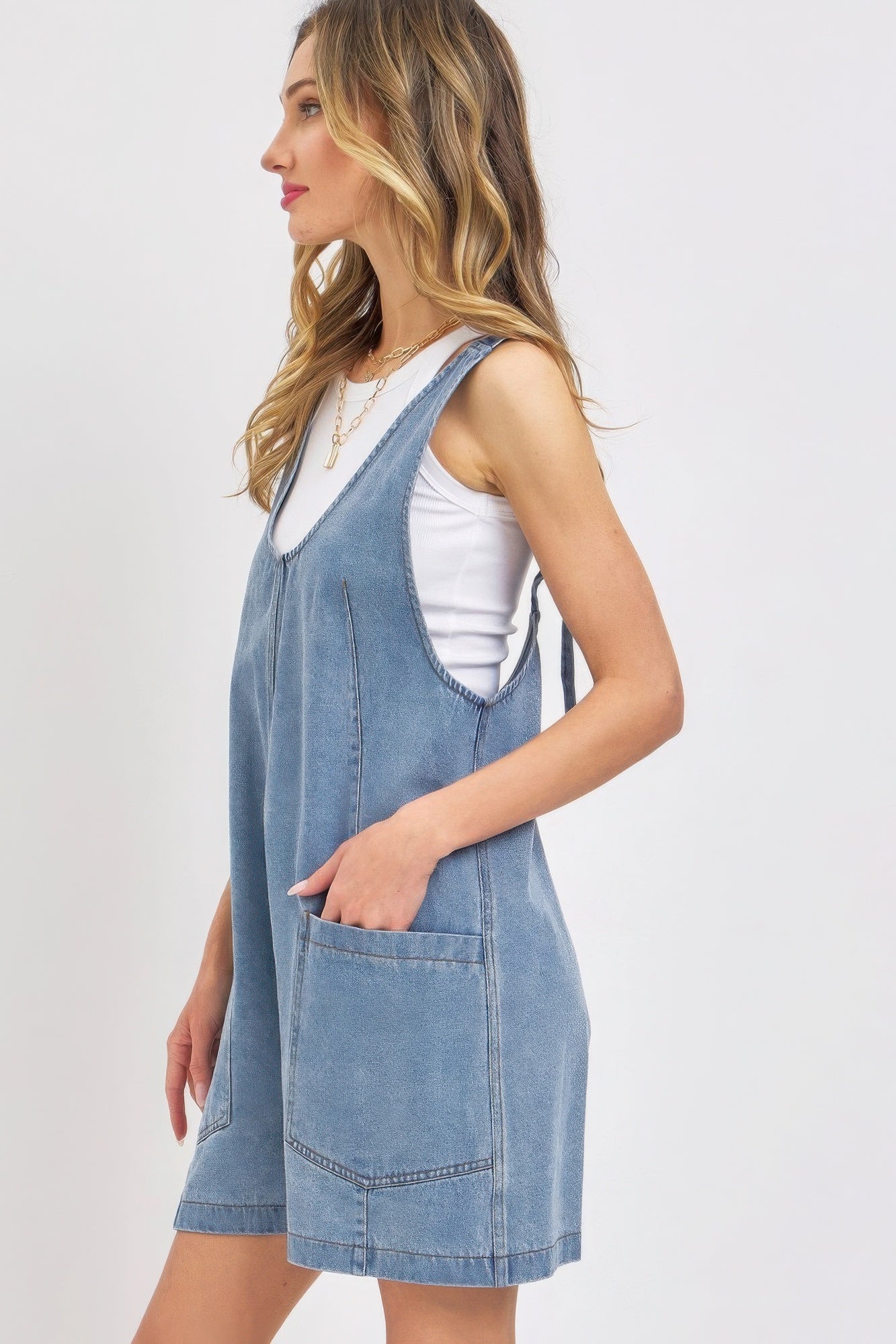 Summer denim romper for women featuring adjustable straps and front pockets in a light blue wash
