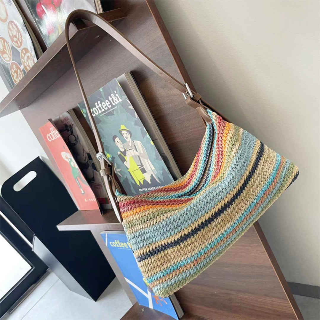 SHOMICOBOUTIQUE summer rainbow straw beach bag displayed on a wooden shelf with colorful books