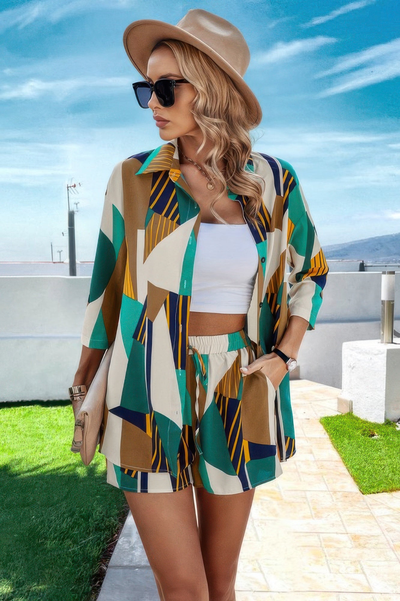 Woman wearing colorful summer resort wear for women outfit with shorts, shirt, white crop top, hat, and sunglasses