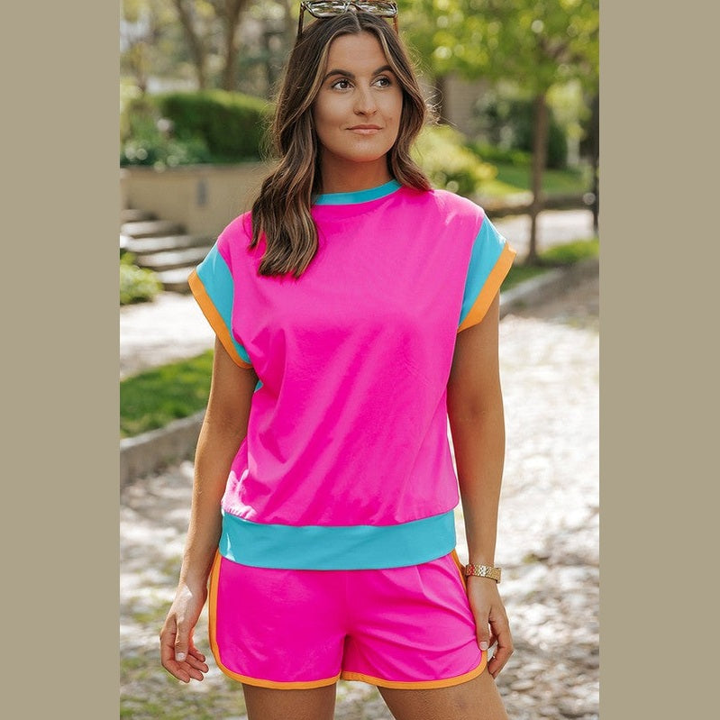 YNIQUE bright pink summer vacation two piece outfit with blue and orange trim on a woman