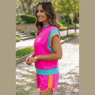 YNIQUE bright pink summer vacation two piece outfit with blue and orange trim worn outdoors