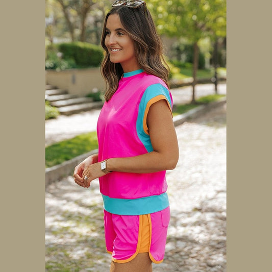 YNIQUE bright pink summer vacation two piece outfit with blue and orange trim worn outdoors