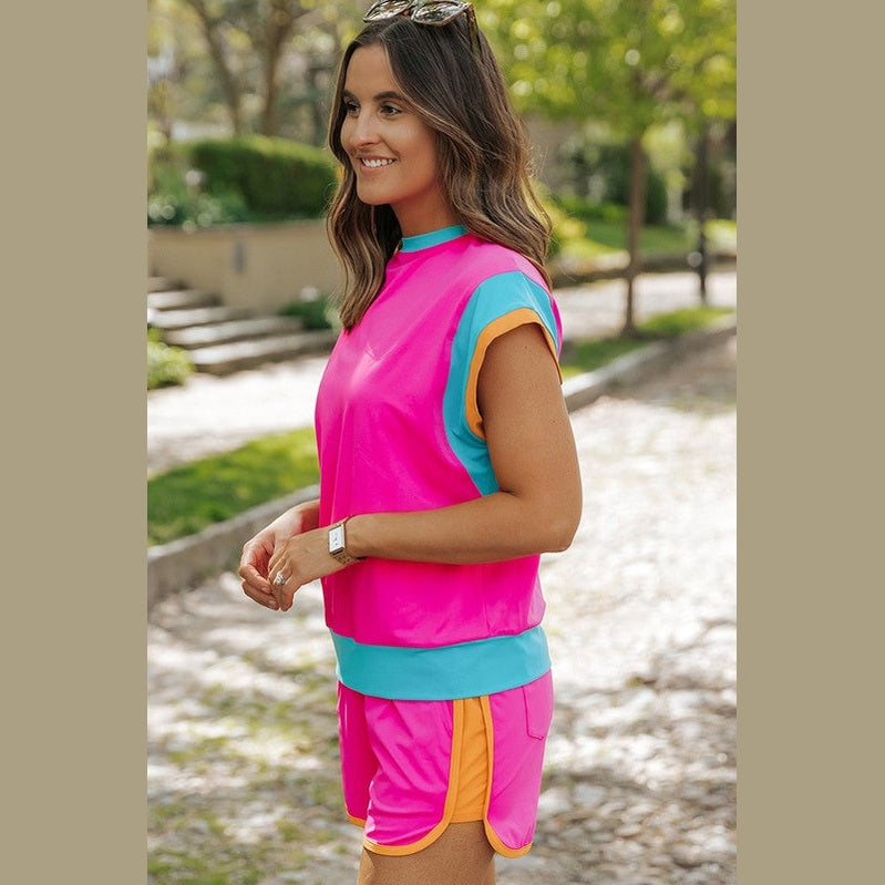 YNIQUE bright pink summer vacation two piece outfit with blue and orange trim worn outdoors