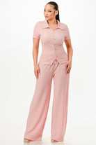 Woman wearing textured pink pants set with short sleeve button-up top and wide leg pants