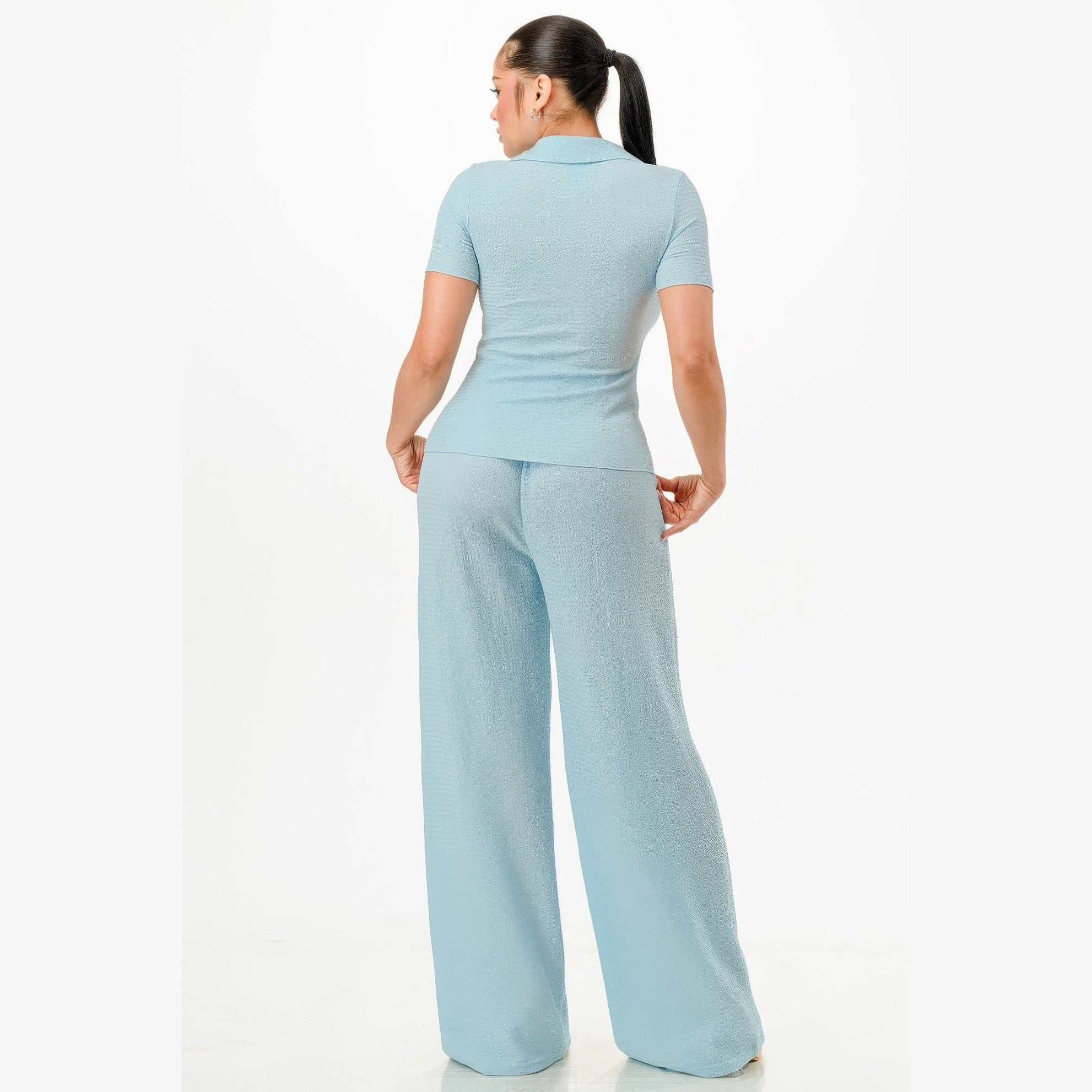 Back view of woman wearing light blue textured polo set for women with short sleeves and wide-leg pants