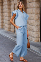 Stylish woman modeling a textured ruffle lounge set in light blue with wide-leg pants and a zip-up top