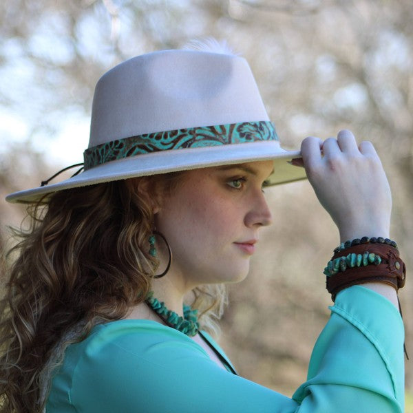 Model wearing a stylish hat and layered jewelry including a leather cuff with natural turquoise