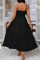 Back view of a black tiered cami vacation dress with adjustable straps and flowy design