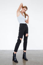 Fashion-forward model wearing trendy black ripped jeans paired with stylish ankle boots