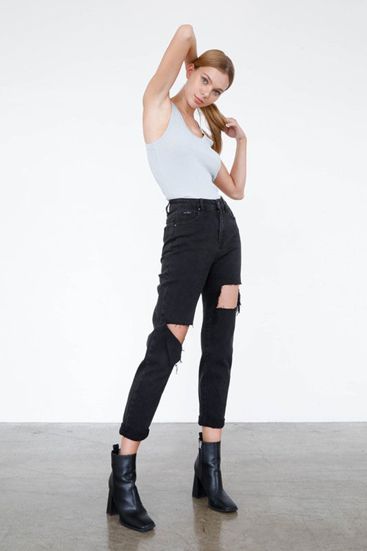 Fashion-forward model wearing trendy black ripped jeans paired with stylish ankle boots