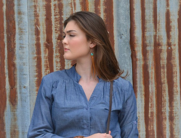 Stylish model wearing turquoise drop earrings with suede tassel, complemented by a denim blouse