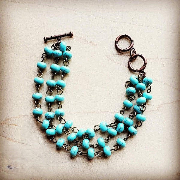 Turquoise triple strand bracelet with copper-tone chain and toggle clasp for a stylish look