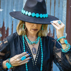 Stylish model wearing a turquoise triple strand bracelet, matching jewelry, and wide-brimmed hat