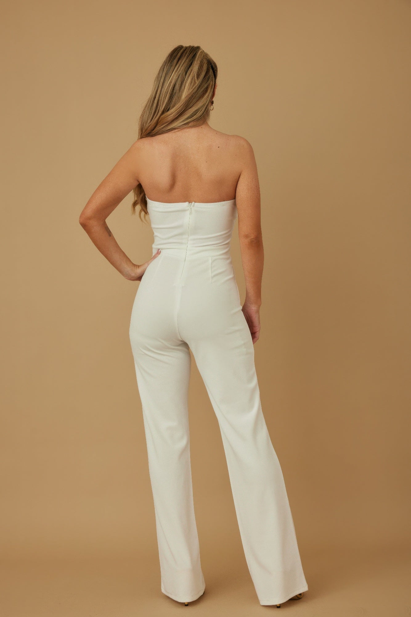 Back view of a white twisted rope knot jumpsuit with a fitted silhouette and flared legs