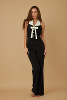 Stylish black vacation jumpsuit outfit for women with a white collar and button details