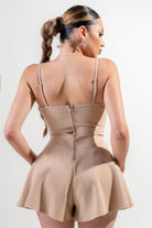 Back view of a tan vacation outfit jumpsuit for women with adjustable straps and a flared hem