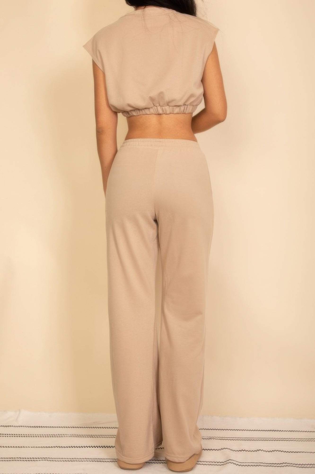 Back view of a beige women's outfit featuring a cropped top and wide-leg pants, perfect vacation outfits for women