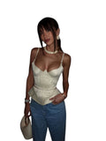 VacationGrabs cream satin corset peplum top with delicate tassel detail worn by a woman in a dimly lit restaurant