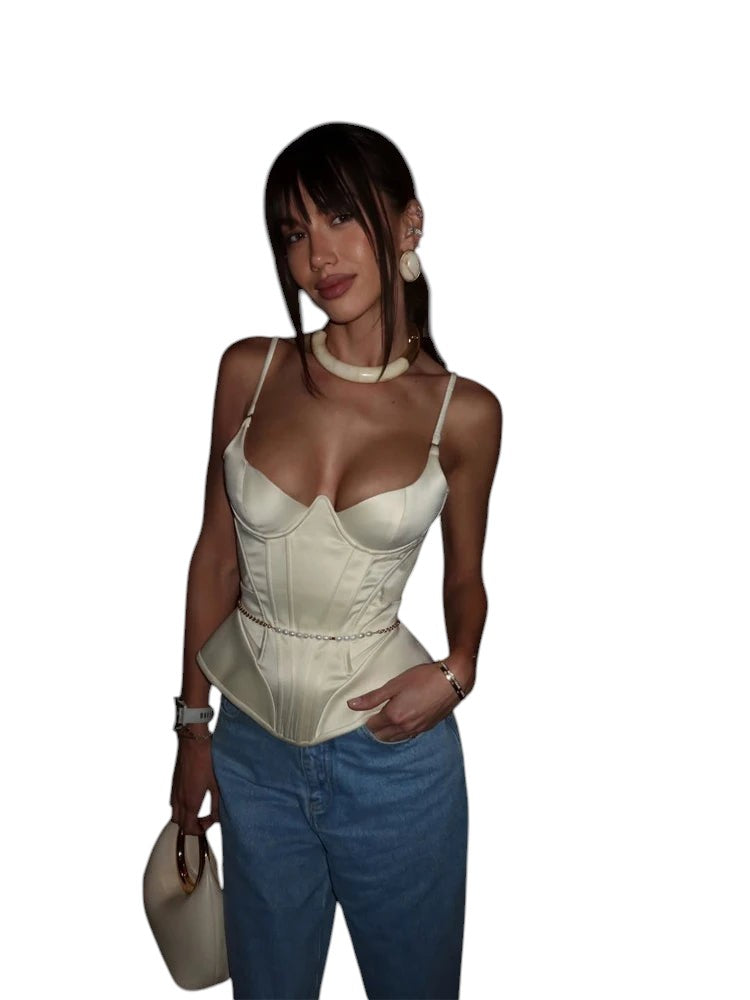 VacationGrabs cream satin corset peplum top with delicate tassel detail worn by a woman in a dimly lit restaurant