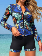 VacationGrabs women's long sleeve zip-up surfing swimsuit set with a tropical leaf print top and solid black shorts.