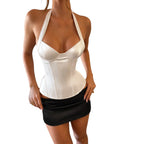 VacationGrabs white satin halter corset top paired with a black mini skirt for a chic night out look