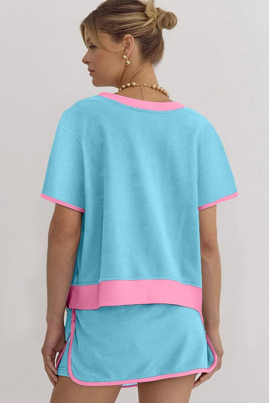 Woman wearing YNIQUE drop shoulder casual summer set in light blue with pink trim, shown from the back