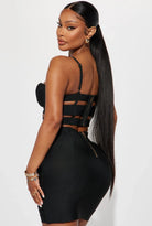 Woman wearing a black edgy party outfit for women with strappy top and fitted skirt