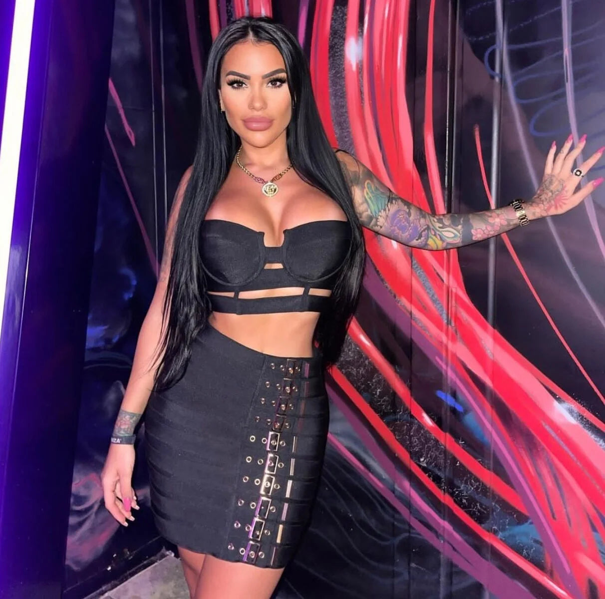 Woman wearing edgy party outfit for women black crop top and skirt with buckle details at night