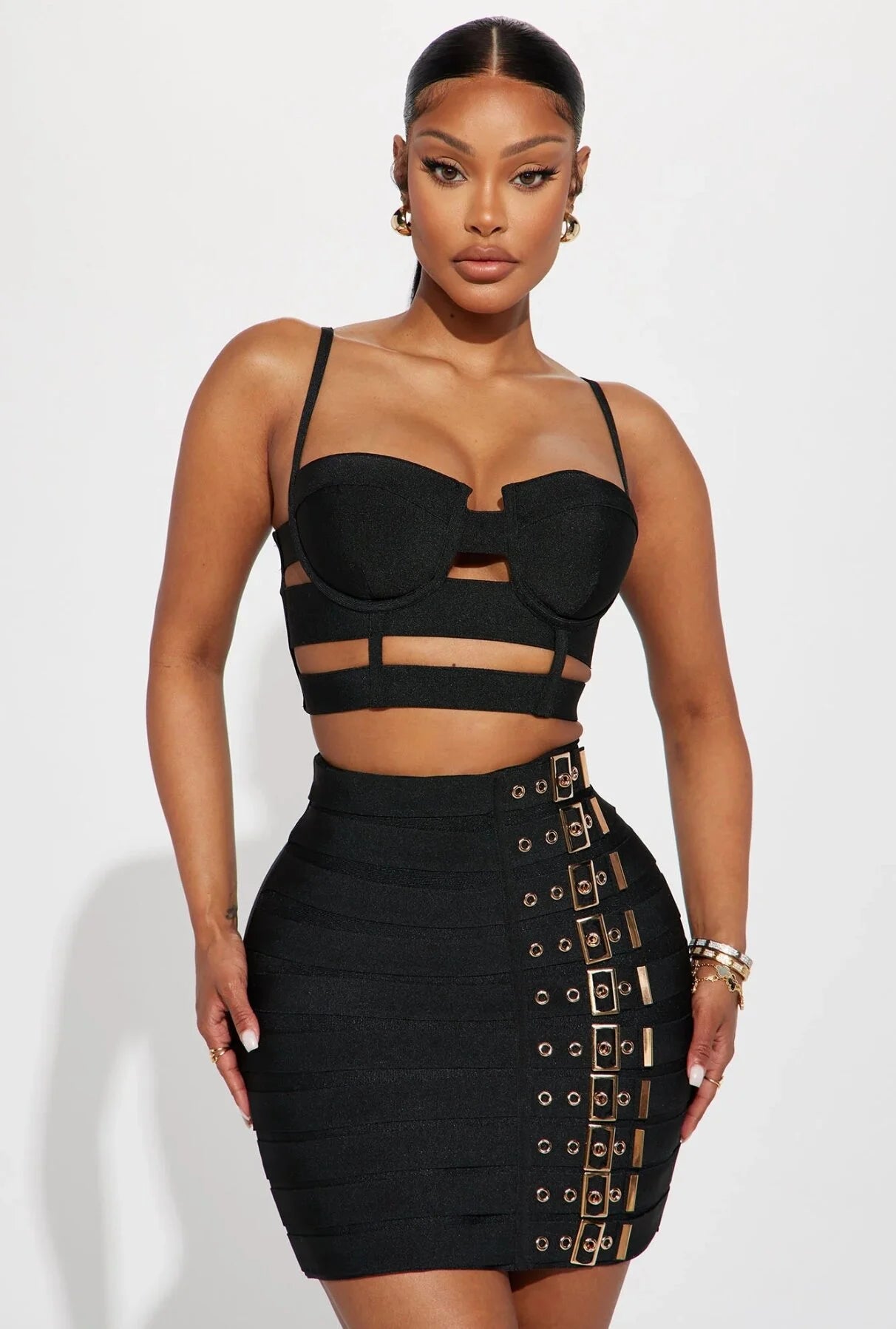 Edgy party outfit for women featuring a black crop top with cutouts and a high-waisted skirt with buckle details