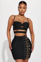 Edgy party outfit for women featuring a black crop top with cutouts and a high-waisted skirt with buckle details