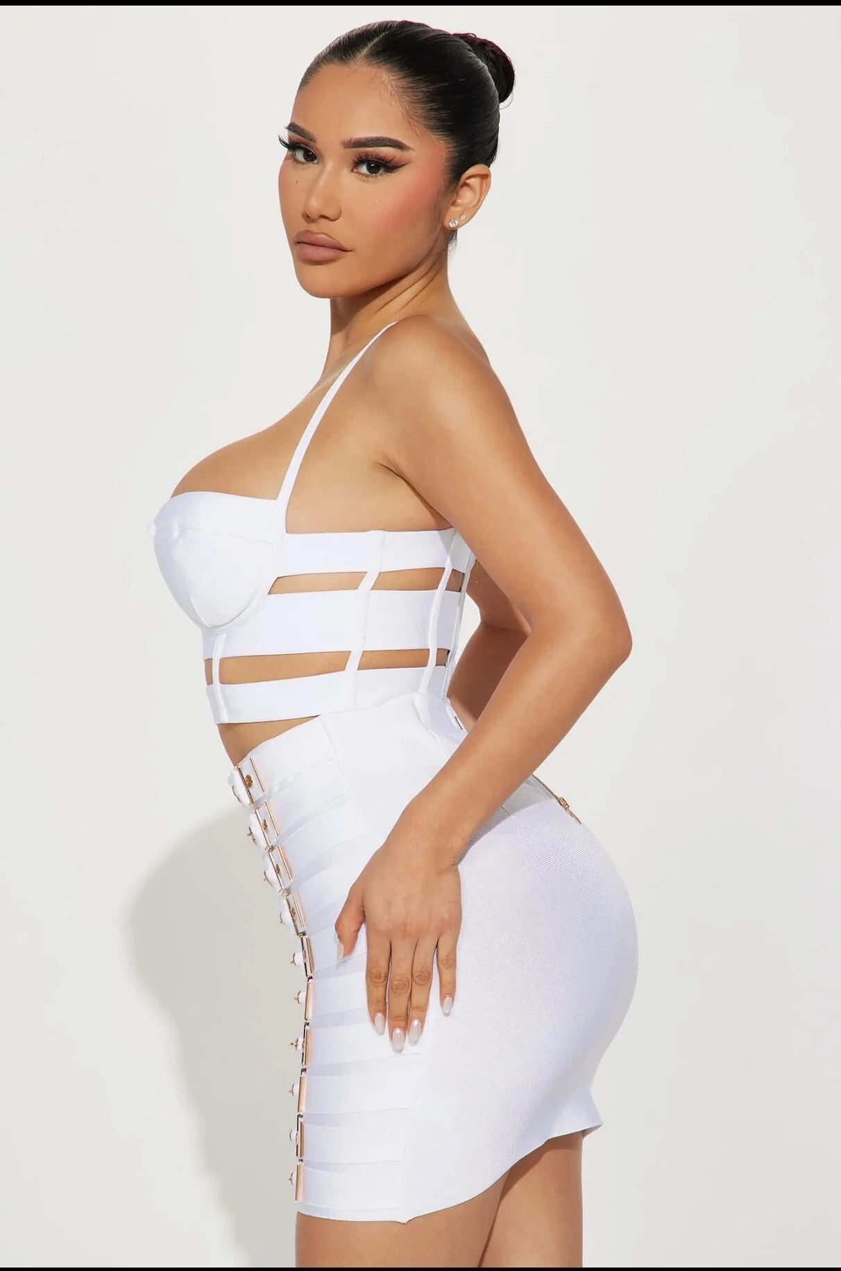 Model wearing a white edgy party outfit for women with cutouts and lace-up sides by VacationGrabs
