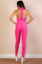 Back view of a pink ribbed bodycon jumpsuit for women with a halter neck and tie detailing