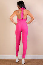 Back view of a pink ribbed bodycon jumpsuit for women with a halter neck and tie detailing