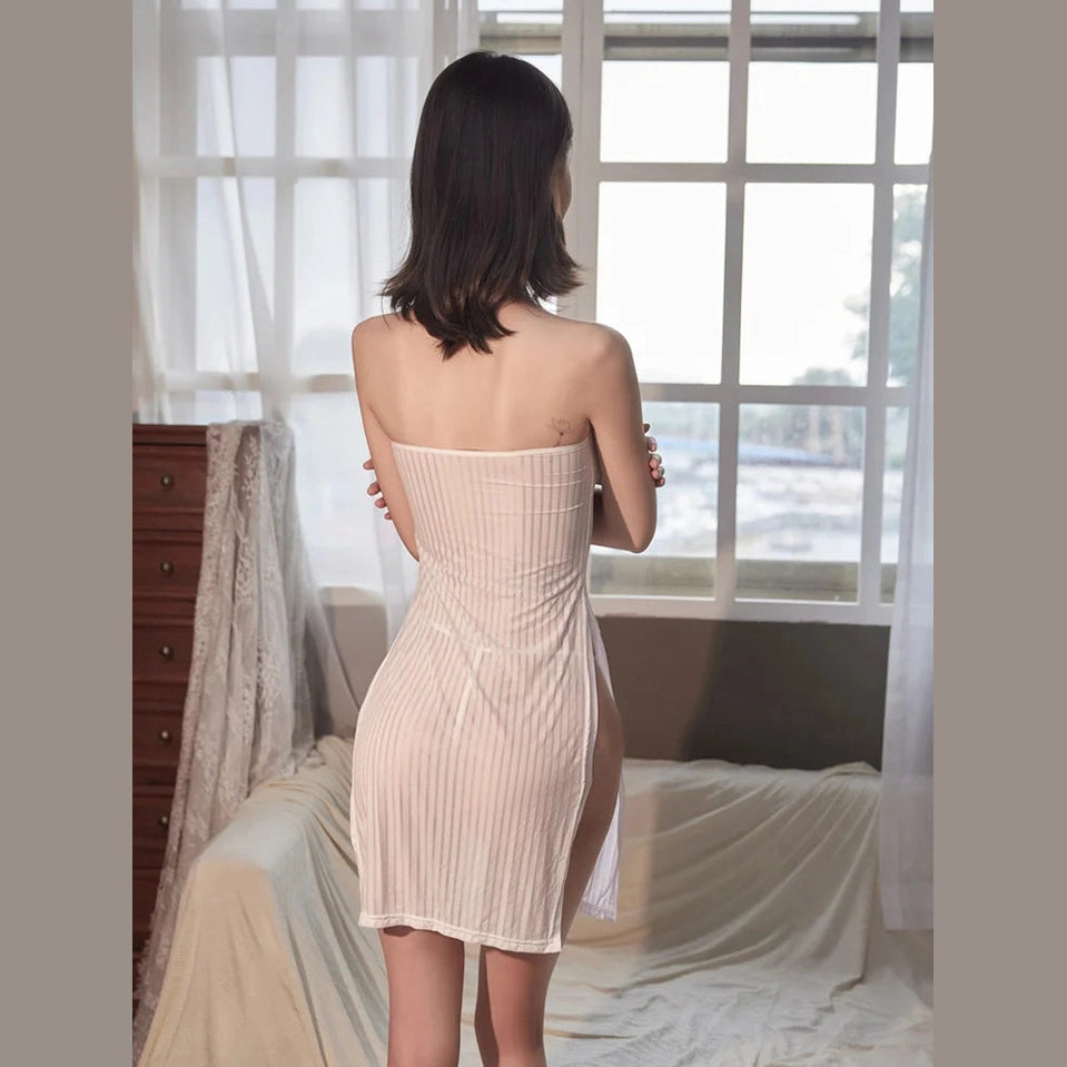 Woman wearing a sexy backless mini dress standing near window in a softly lit room