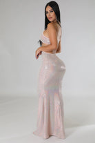Woman wearing a shiny pink sexy vacation maxi dress with thin straps and a fitted silhouette