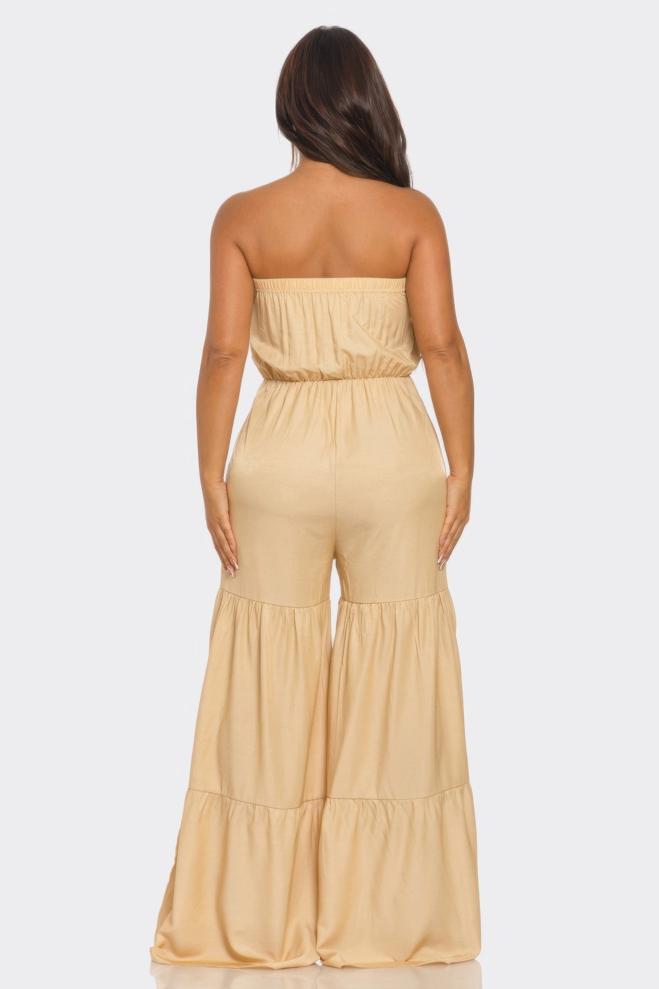 Back view of a strapless vacation jumpsuit in beige with wide legs and elastic waistband
