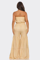 Back view of a strapless vacation jumpsuit in beige with wide legs and elastic waistband