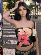 Woman wearing a black summer strapless crop top with large pink and orange floral print in city street