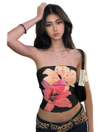 Woman wearing a black summer strapless crop top with large pink and orange floral print in city street