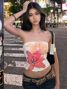 Young woman wearing summer strapless crop top with large floral print standing on city street at night