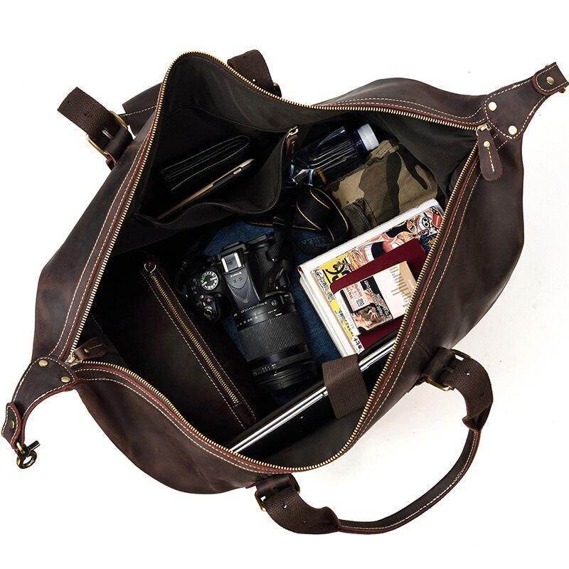 Vintage leather travel bag with spacious interior holding a camera, books, and personal items