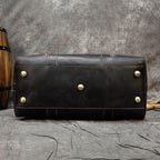 Bottom view of vintage leather weekender bag showcasing sturdy brass feet and authentic leather craftsmanship
