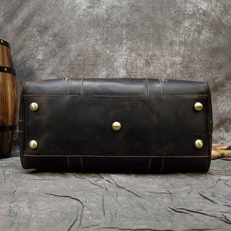 Bottom view of vintage leather weekender bag showcasing sturdy brass feet and authentic leather craftsmanship