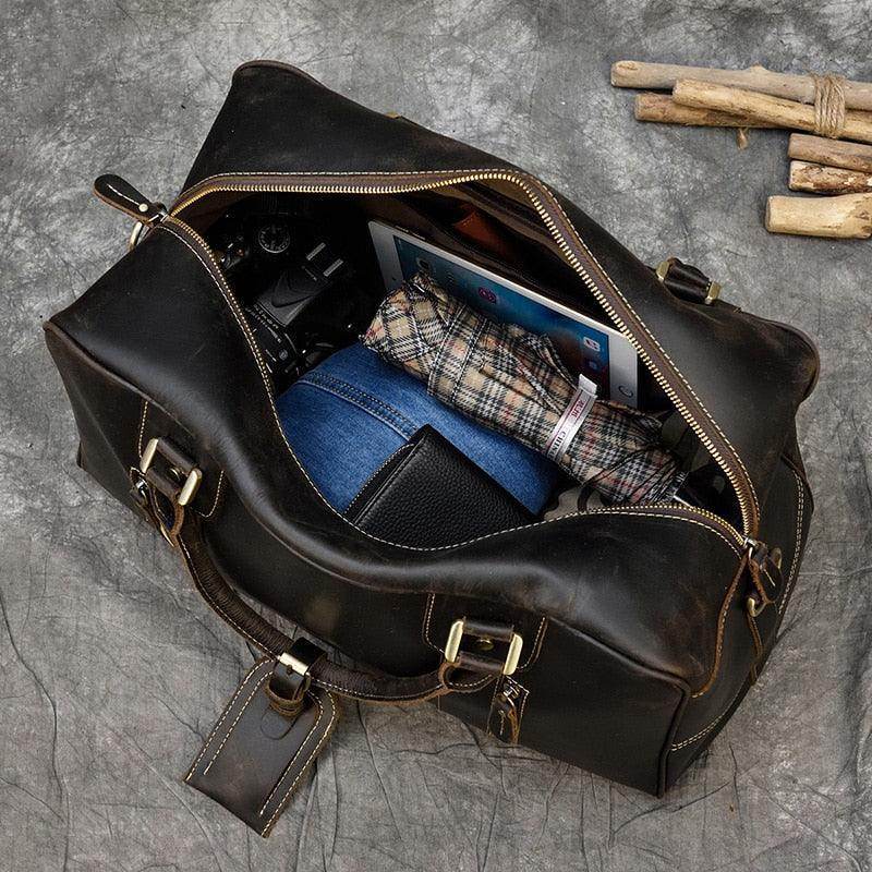Vintage leather weekender bag open showing packed clothes and accessories inside for travel