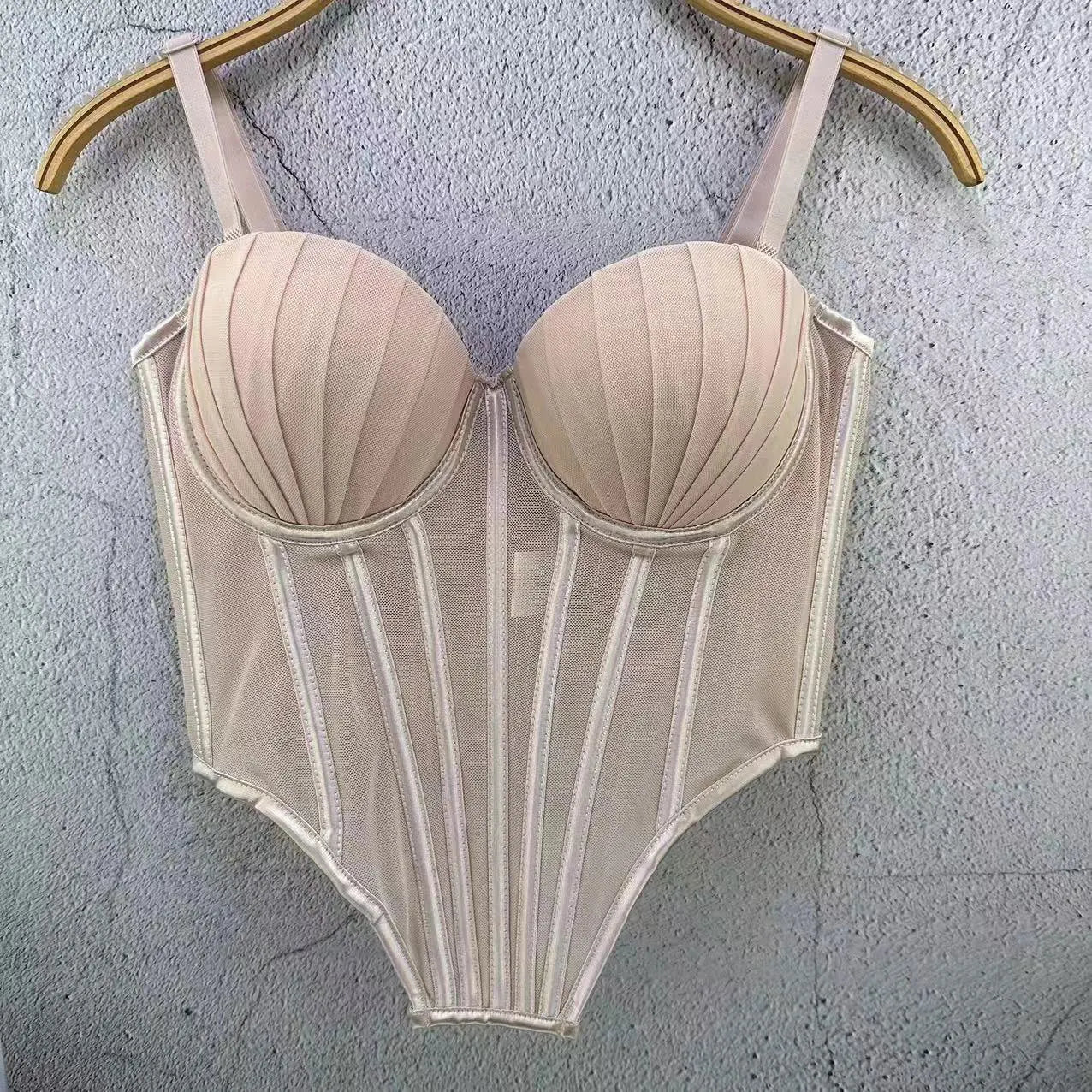 Beige sexy clubwear bustier shirt with structured cups and vertical panel detailing hanging on wooden hanger