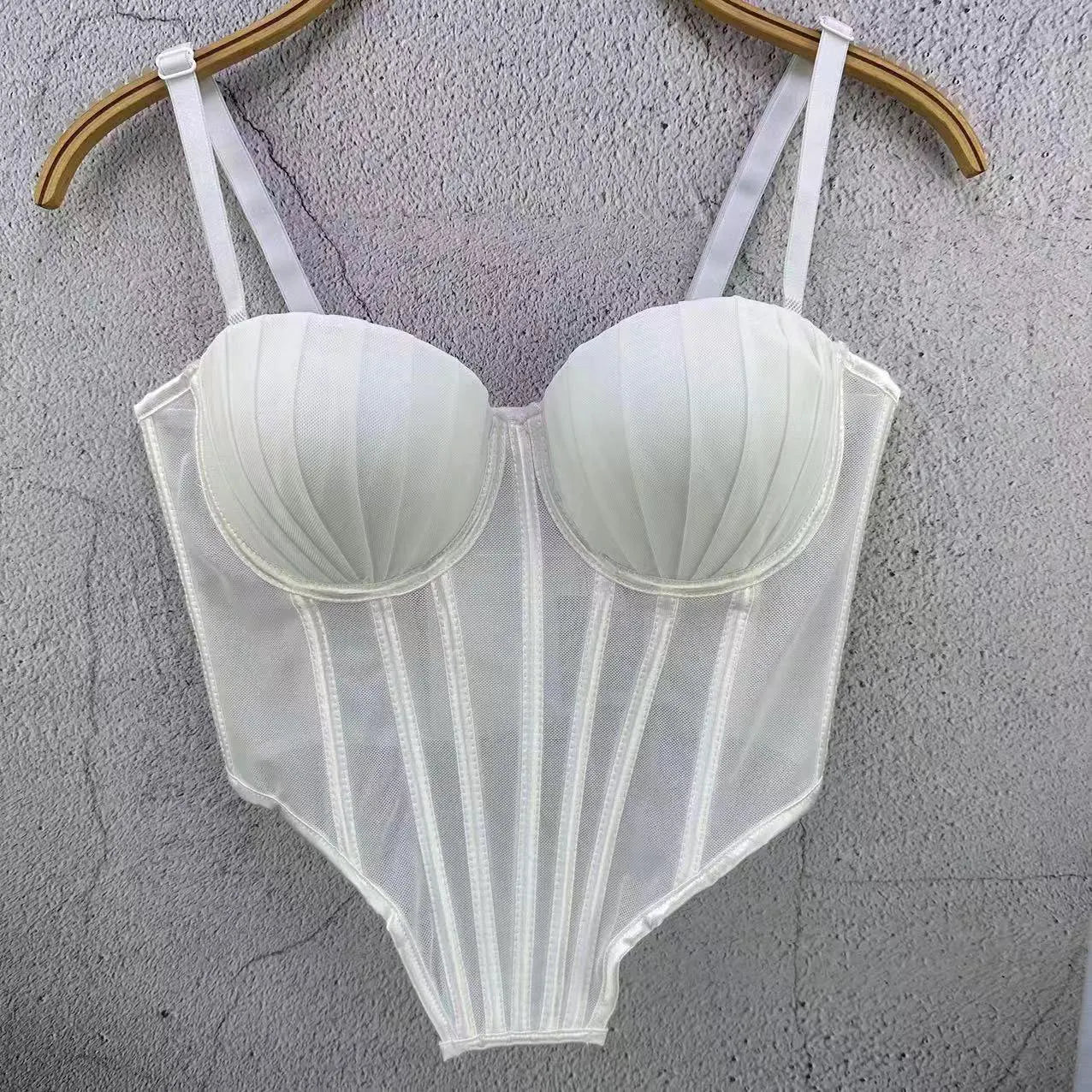 White sexy clubwear bustier shirt with structured cups and adjustable straps hanging on a wooden hanger